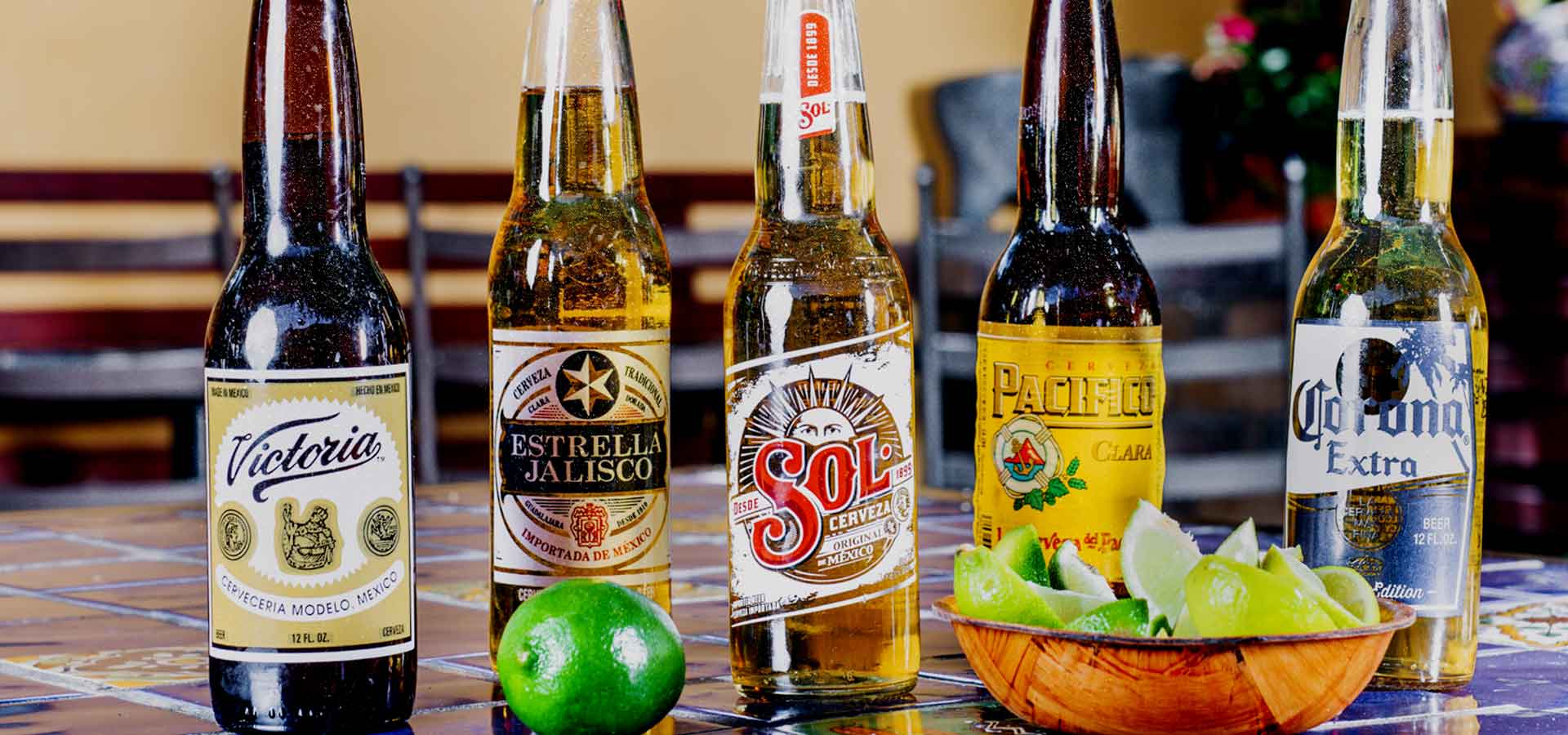 Five different bottles of beer with a side of lime slices