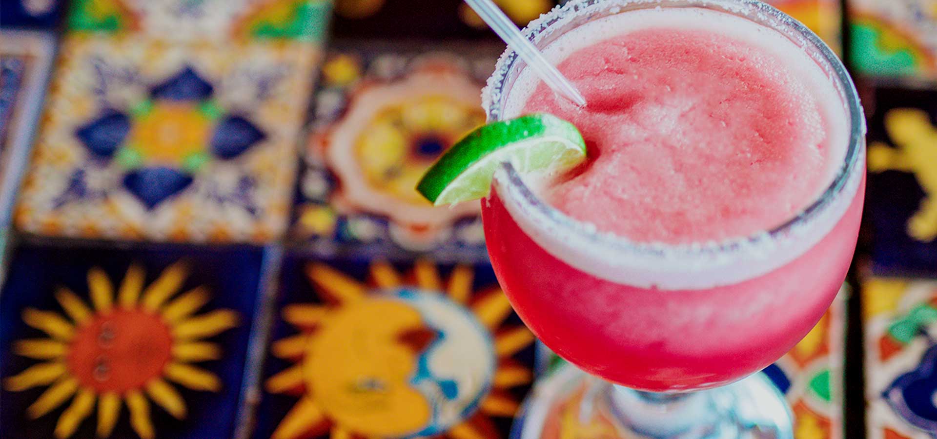 A refreshing frozen strawberry margarita with a slice of lime